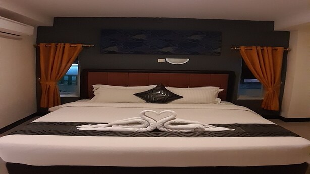 A hotel room with a large bed, two curtains, a headboard, and a wall-mounted artwork. - New Hotel Gentala (Medan)