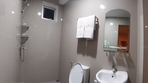 A modern bathroom with a toilet, sink, shower, and a small window. - New Hotel Gentala (Medan)
