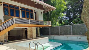 Una piscina con cubierta de madera y pared de piedra.