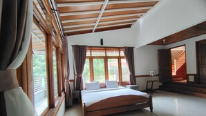 Un dormitorio amplio con una cama grande, vigas de madera en el techo y ventanas grandes con cortinas.