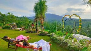 Ein tropischer Garten mit einer herzförmigen Blumendekoration und Blick auf ein Gebirge.