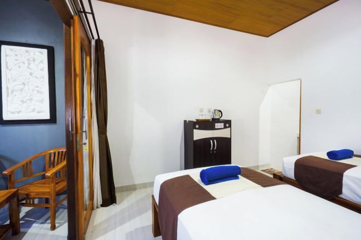 Una habitación de hotel con dos camas, una silla de madera, un escritorio y un armario.