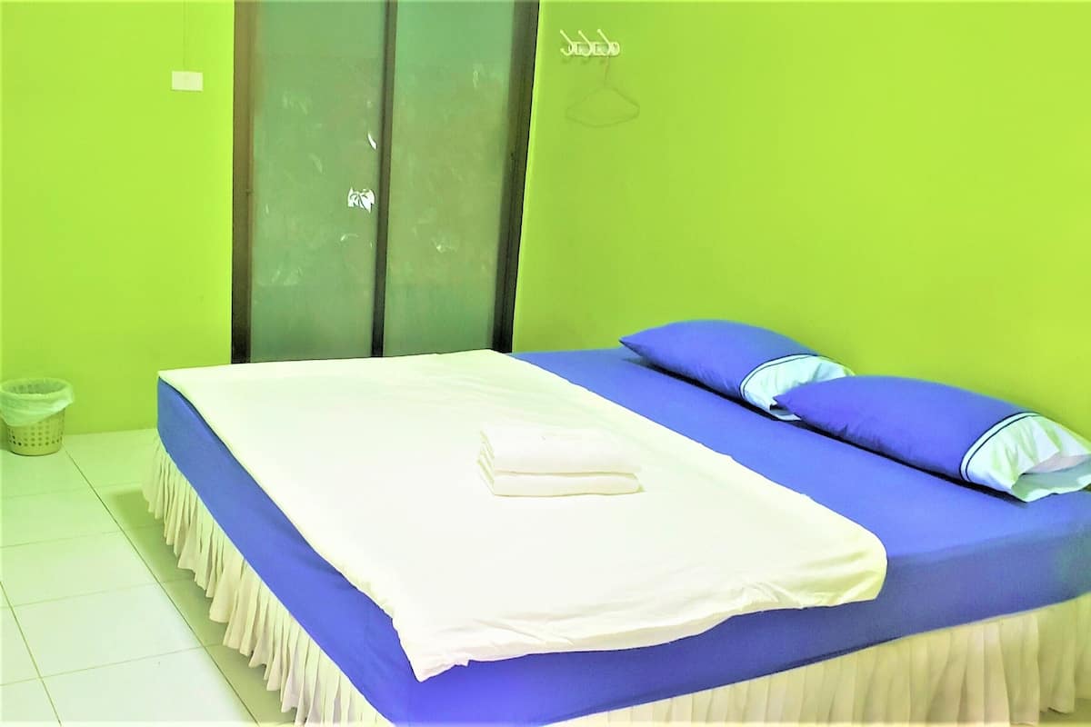 A bed with a white and blue bedspread, a blue pillow, and a white pillow.
