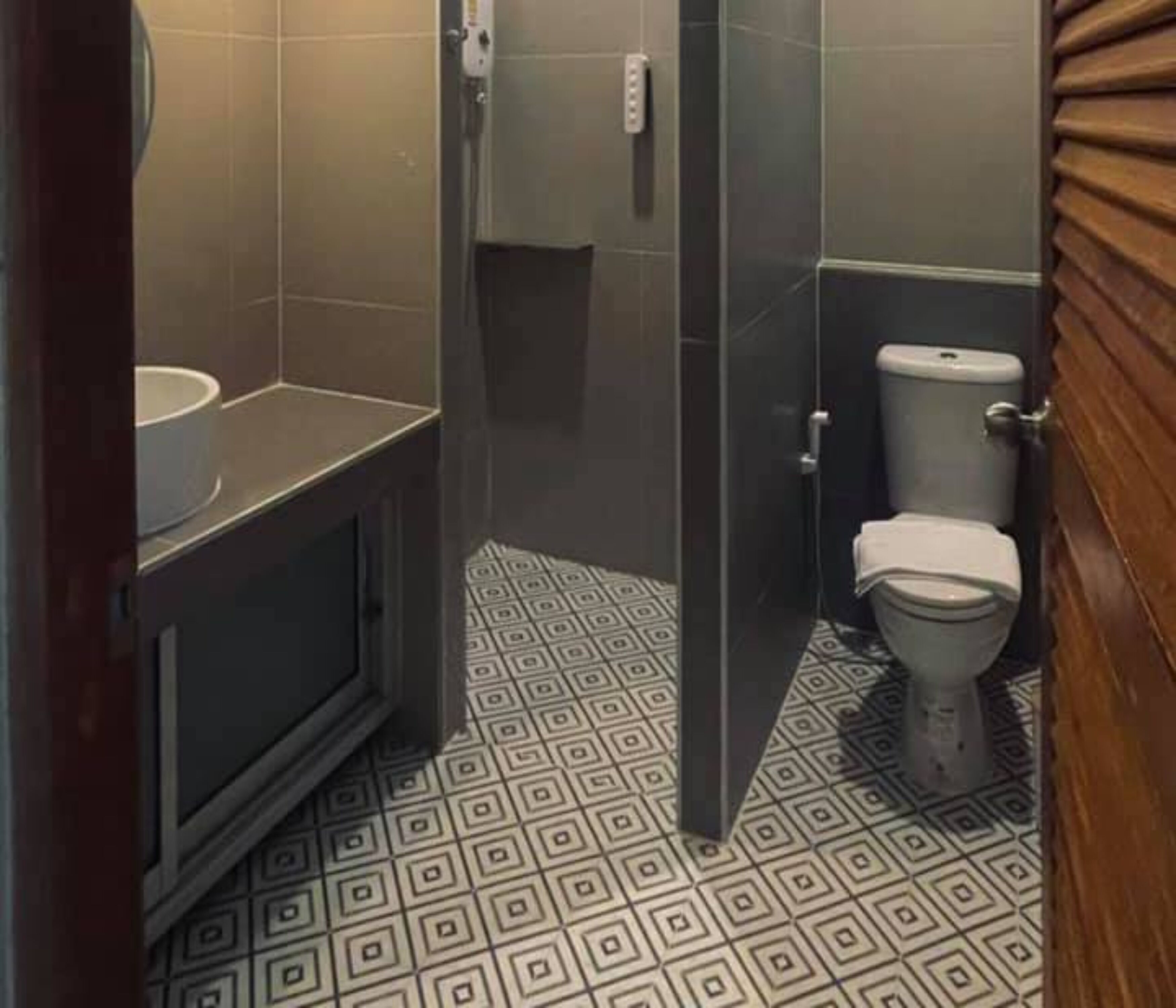 Egy mintás padlós, WC-vel és mosdókagylóval felszerelt fürdőszoba.