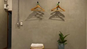 A hotel room with a bed, a bedside table with a plant, and two wooden hangers on the wall. - Baan Chiang Bed Lampang (Lampang)