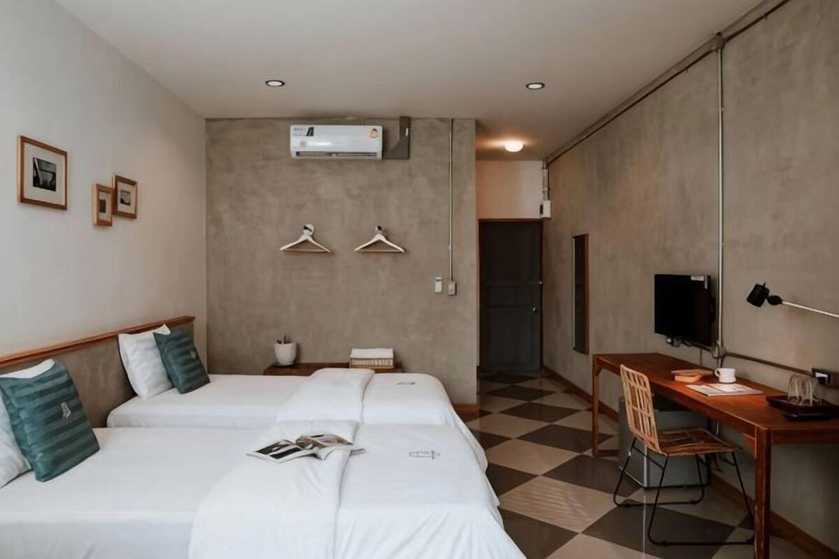 Een hotelkamer met twee bedden, een bureau, een stoel, een televisie en een kapstok.
