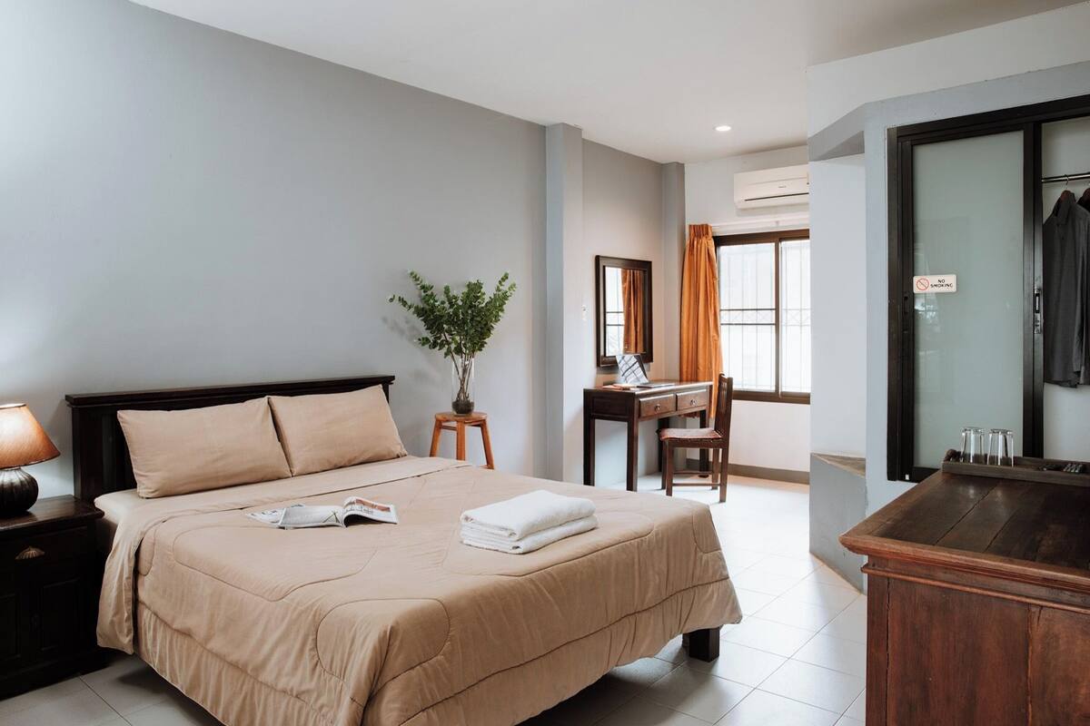 Een hotelkamer met een bed, een bureau, een stoel, een plant en een kledingkast.