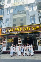 Un restaurante llamado "Com Meu Viet Nam" con un letrero que muestra su nombre y número de contacto.