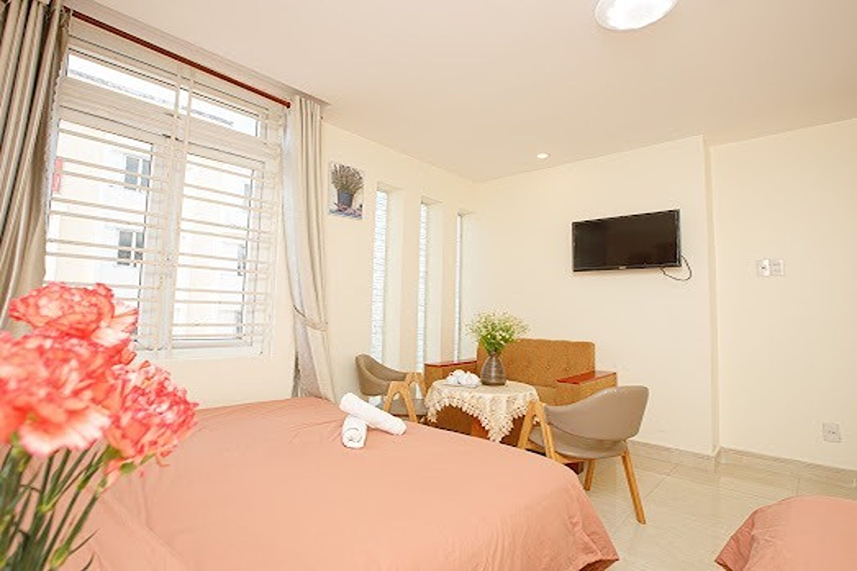 A hotel room with a bed, a desk with a chair, a television, and a window with curtains.
