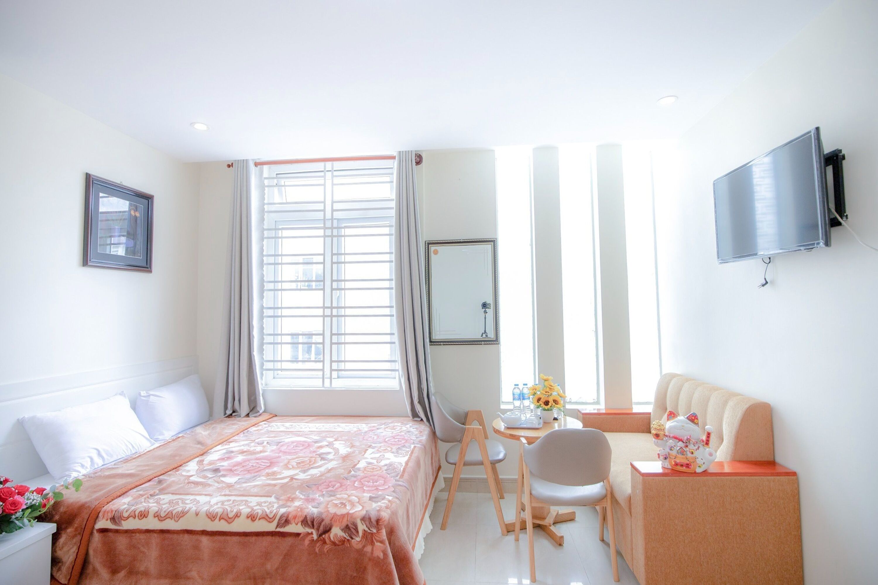Une chambre d’hôtel avec un lit, un bureau, une chaise, une télévision et une fenêtre avec des rideaux.
