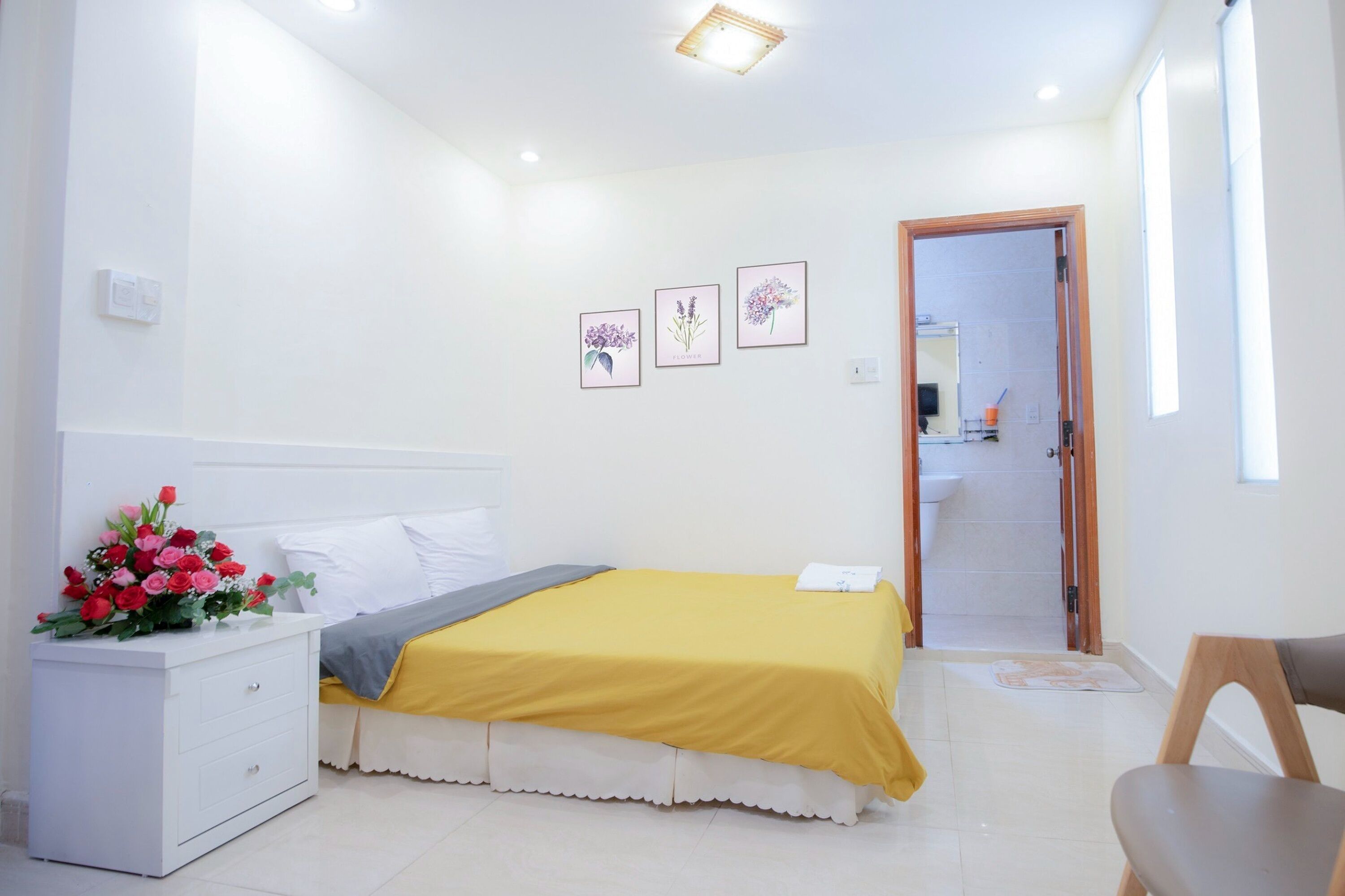 A bedroom with a bed, a nightstand, a chair, and a door leading to a bathroom.
