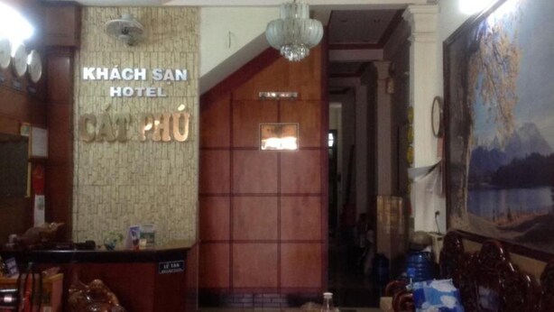L’intérieur de l’hôtel Khach San comprend un comptoir d’accueil, un mur en bois avec une enseigne et un tableau représentant un paysage de montagne.