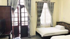 Une chambre d’hôtel avec un lit, une télévision et des rideaux.
