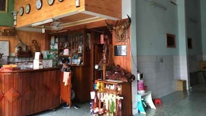 A wooden interior with a reception desk, clocks, and various items on shelves. - Thanh Binh Hotel Pleiku (Dien Hong)