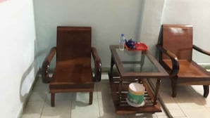 A small room with two wooden chairs and a glass table. A water bottle and a red tray are on the table. - Thanh Binh Hotel Pleiku (Dien Hong)