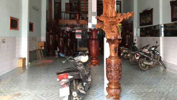 A spacious lobby with a high ceiling, a wooden statue, and several motorcycles parked. - Thanh Binh Hotel Pleiku (Dien Hong)