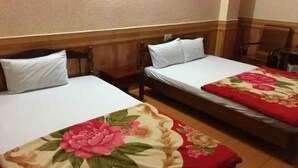 A hotel room with two single beds, each with white linens and a wooden headboard. The room has a wooden floor and a beige wall. - Thanh Binh Hotel Pleiku (Dien Hong)