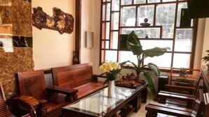 Een woonkamer in traditionele stijl met een bank, een salontafel en een groot raam met uitzicht op groen.