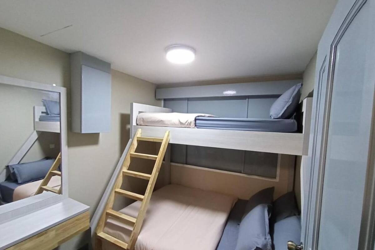 A bunk bed with a ladder, a desk, and a mirror.