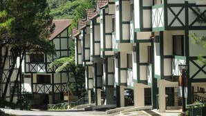 A row of traditional-style buildings with a symmetrical facade, featuring a mix of white and dark green panels and a central staircase leading to the entrance. - Zarania Hillhomes Cameron Highlands (Brinchang)