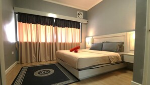 A bedroom with a bed, a nightstand, a clock, and a window with curtains. - Zarania Hillhomes Cameron Highlands (Brinchang)