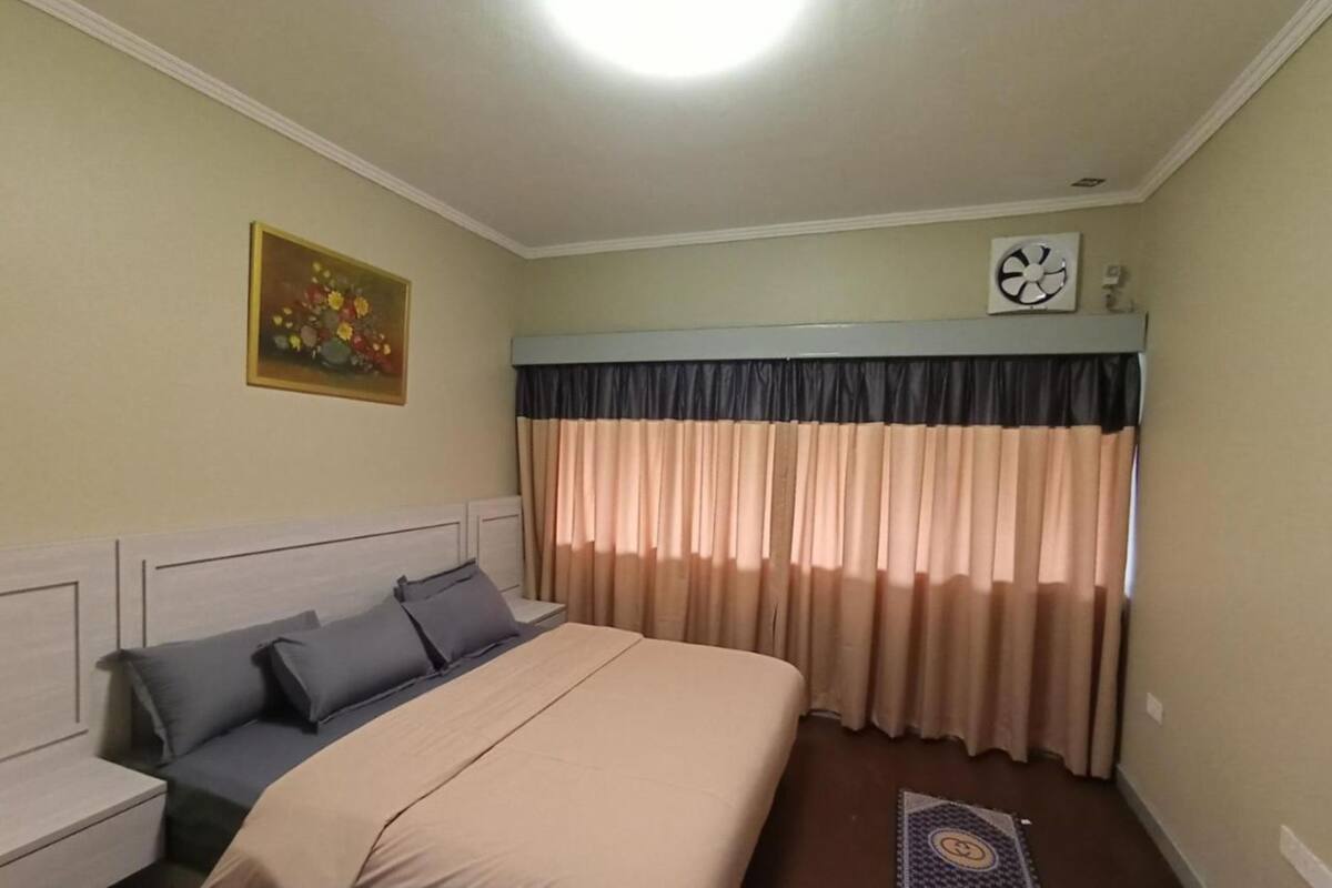 A bedroom with a bed, nightstands, a wall clock, and a painting.