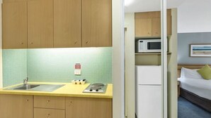 Eine kleine Küche mit Holzschränken, einer Spüle, einer Mikrowelle und einem Kühlschrank.