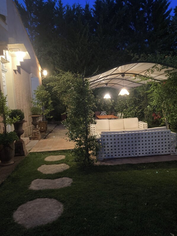 A patio area with a covered seating area, potted plants, and a pathway.