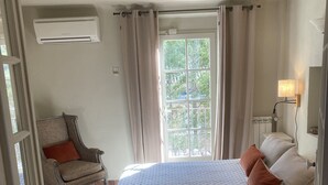 A bedroom with a large bed, a chair, a window with curtains, and an air conditioning unit. - The Bastide of Villecroze  (Villecroze)