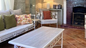 A cozy room with a stone wall, a fireplace, a sofa with cushions, a table, and a lamp. - The Bastide of Villecroze  (Villecroze)