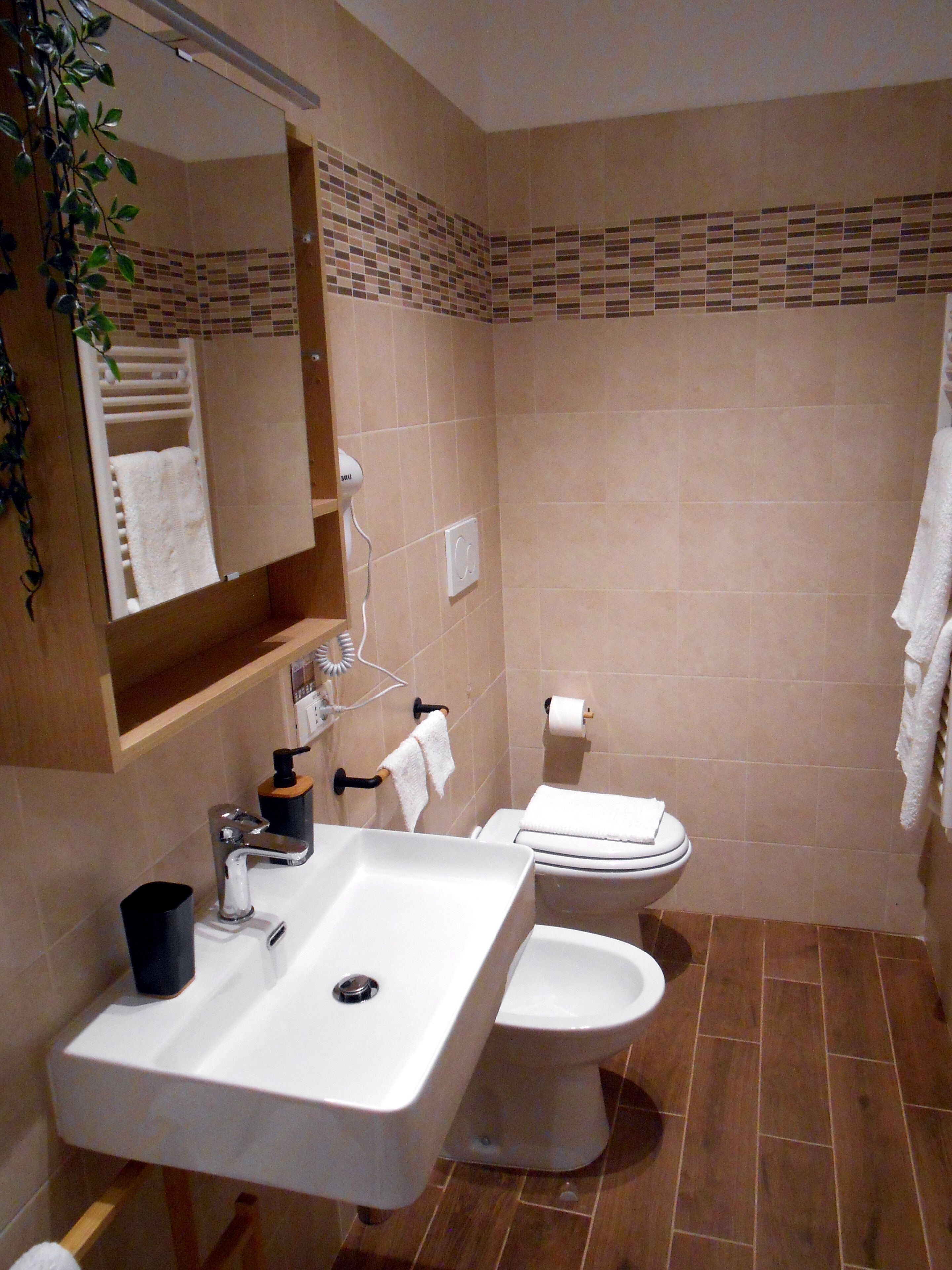 Een badkamer met een wastafel, toilet en spiegel.