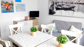 Een moderne kamer met een eettafel, stoelen, een bank, een televisie en een groot stadslandschap schilderij.