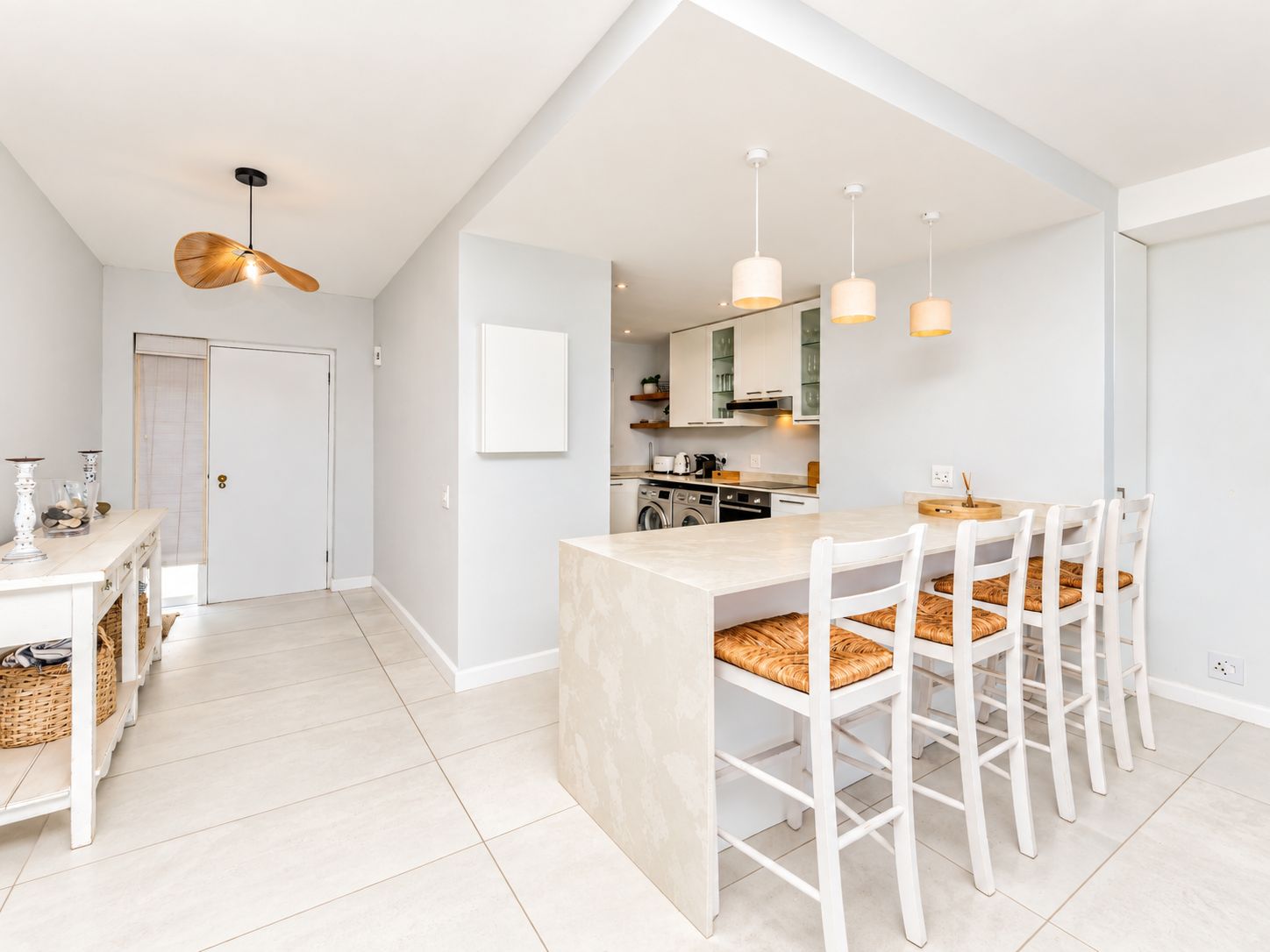 A modern kitchen with a central island, white cabinetry, and pendant lighting.