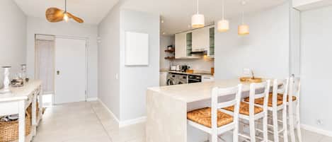 A modern kitchen with a central island, white cabinetry, and pendant lighting.