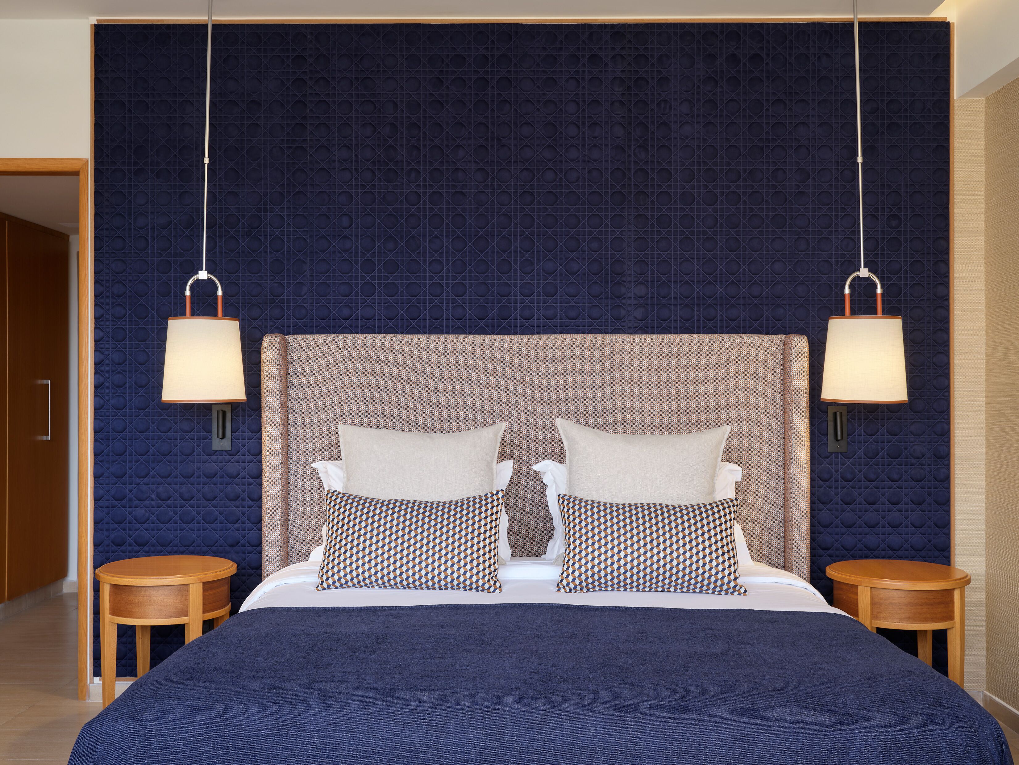 A double bed with a patterned headboard, two bedside tables, and wall-mounted lamps.