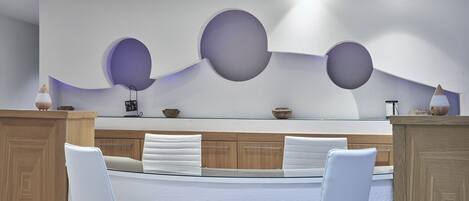 Une cuisine moderne dotée d’un îlot central, de chaises blanches, de meubles en bois et d’un décor mural original avec des découpes circulaires.