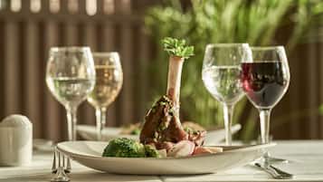 A dining table with a plate of food, two wine glasses, and a decorative plant.