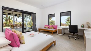 A modern hotel room with a bed, desk, and large windows offering a view of palm trees and a balcony. - Villa Bloom by Villa Finder (Sukasada)