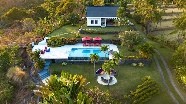 A large house with a swimming pool, surrounded by lush greenery and palm trees. - Villa Bloom by Villa Finder (Sukasada)