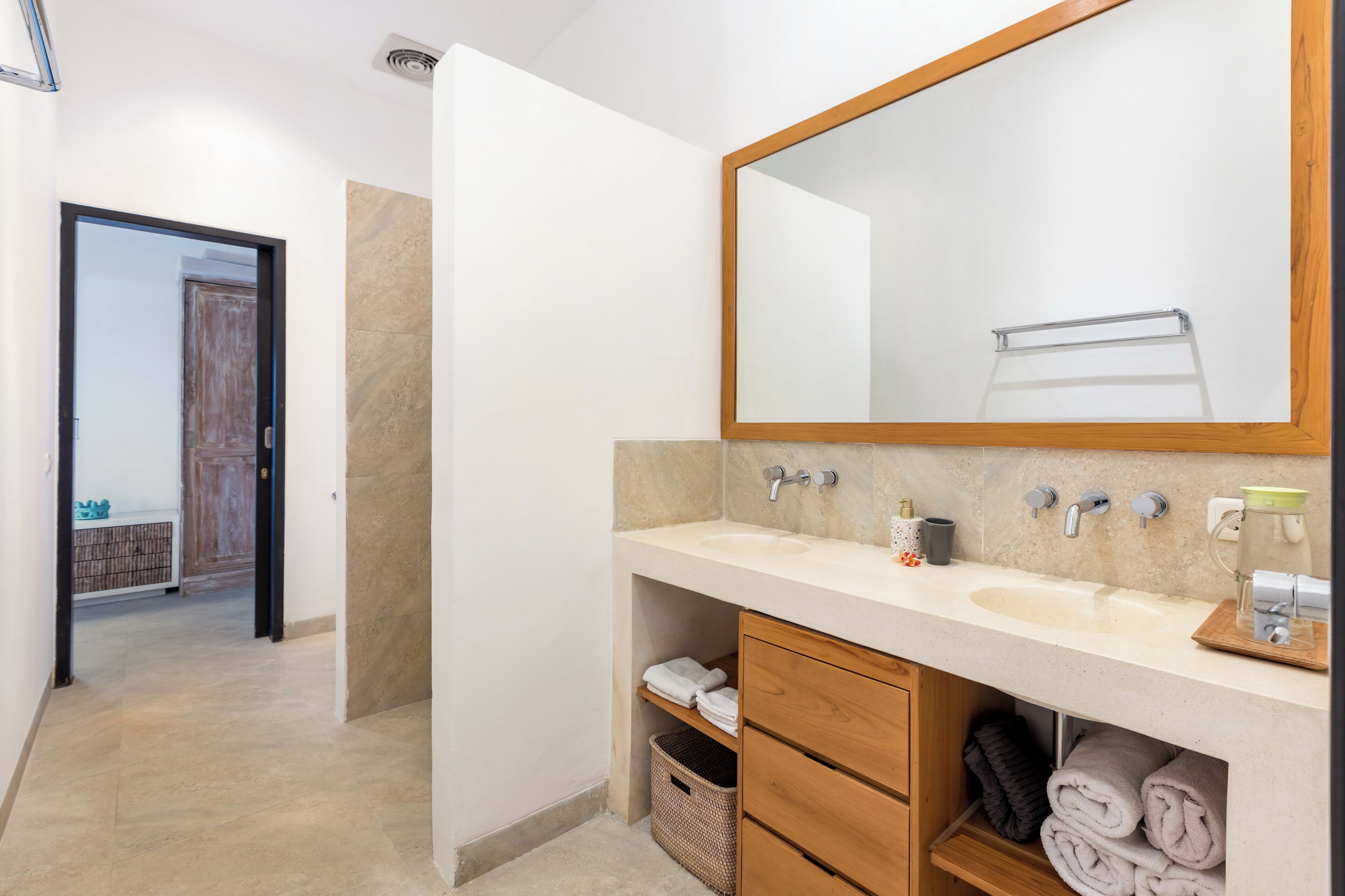 A modern bathroom with two sinks, a large mirror, and a wooden vanity.