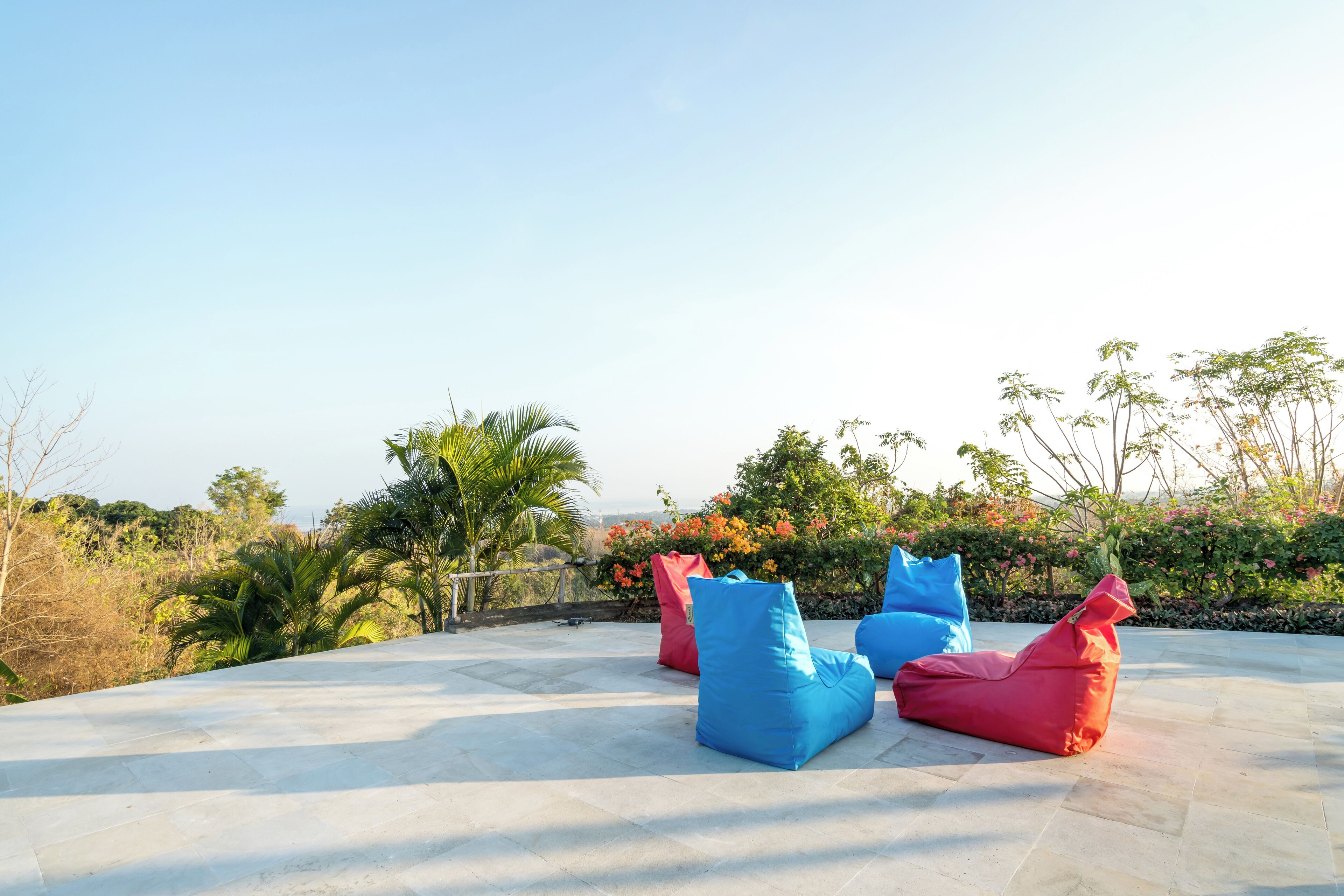 Outdoor seating with a view of a landscaped garden and distant hills.