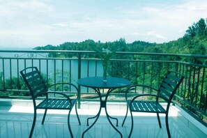 A balcony with a round table and two chairs, overlooking a forested area. - King Room With Nice Lake View - 2 People (Bwishyura)