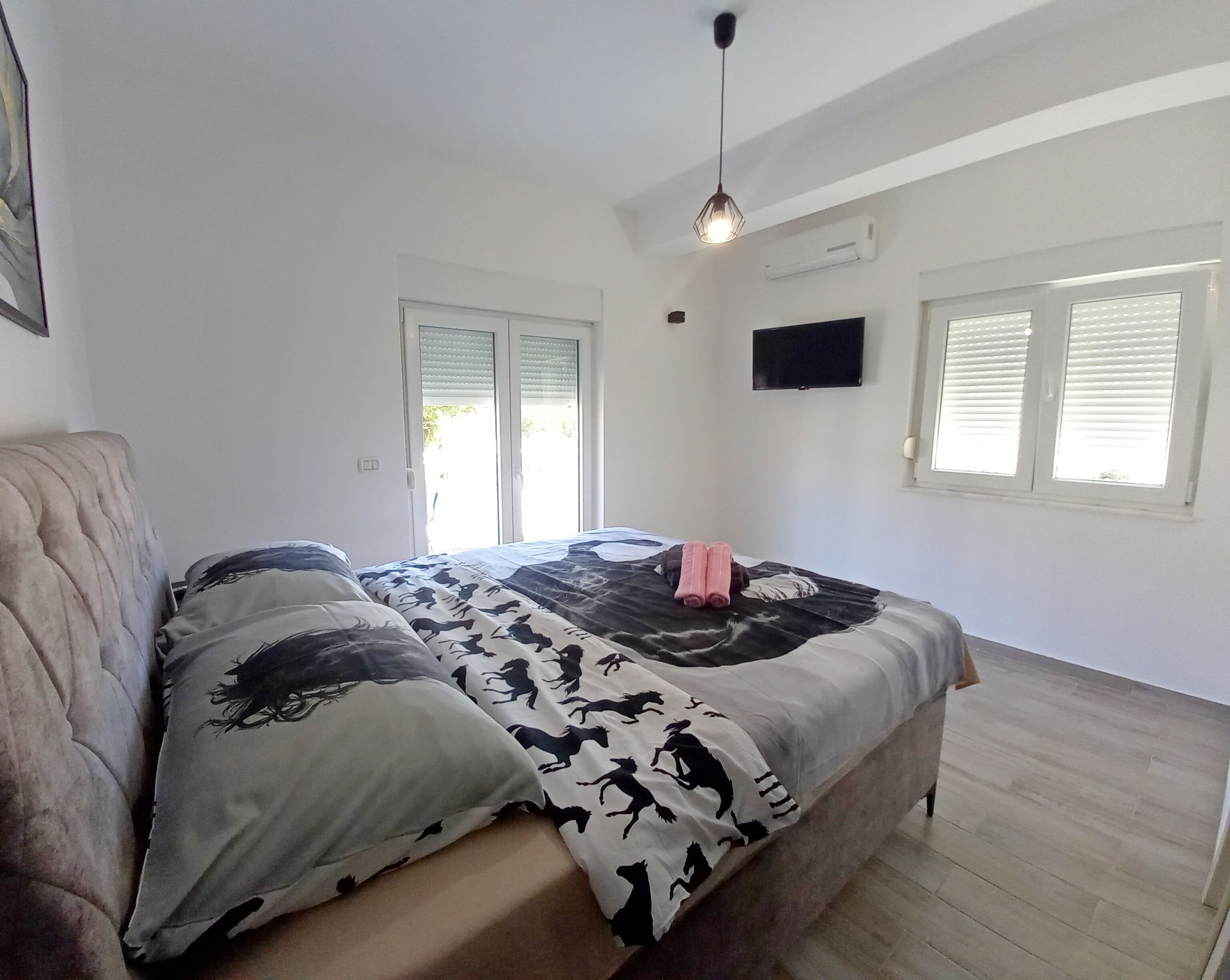 Une chambre à coucher avec un lit, une télévision et une fenêtre équipée de stores.