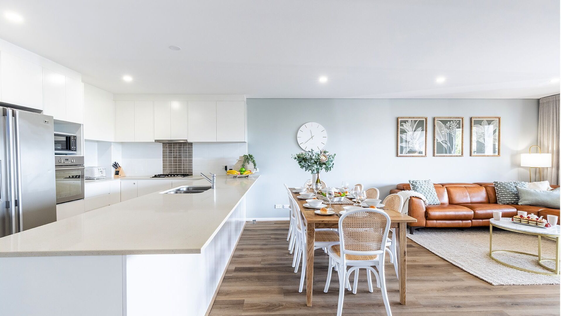 Una cocina moderna con armarios blancos, una isla central y electrodomésticos de acero inoxidable.