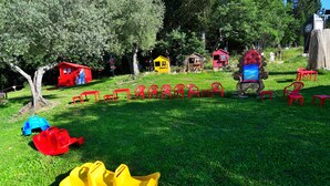 A grassy area with play structures, including a slide and small houses, and a row of red chairs. - COUNTRY RESORT THE ASH (Toscana)