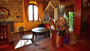 A wooden table with a bottle of champagne, a pineapple, and two glasses. - COUNTRY RESORT THE ASH (Toscana)