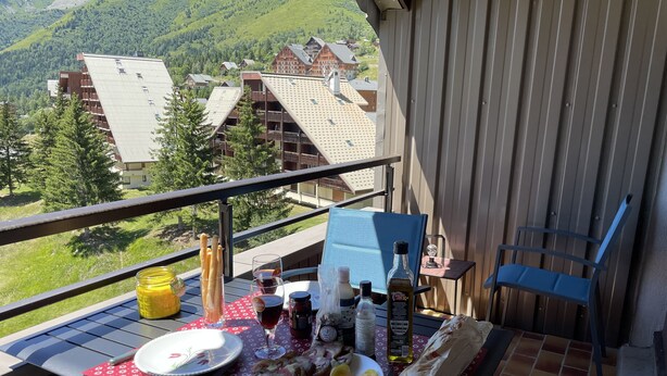 Un balcon avec une table dressée pour un repas, offrant une vue sur un paysage montagneux.