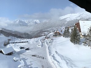 Ein verschneites Bergdorf mit Häusern und einer Skipiste.