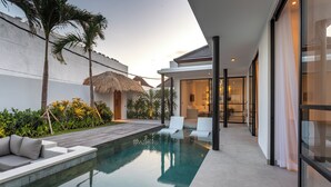 A modern outdoor pool area with a thatched-roof structure, a wooden deck, and a glass-enclosed lounge area. - Villa Lapis by Villa Finder (Canggu)