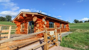 A log cabin with a wooden deck and a gate. - Cedar Cabin at Salford Court Farm Fishing Cabins (Worcester)